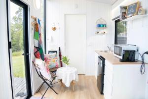 马莱尼White Jacaranda Tiny House by Tiny Away的小房子里的厨房，配有一张桌子和一把椅子。