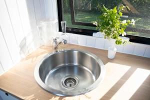 马莱尼White Jacaranda Tiny House by Tiny Away的厨房里的一个不锈钢水槽,窗户 更多25张照片