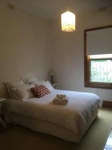 a bedroom with a large white bed with two towels at Maylands Cottage in Evandale