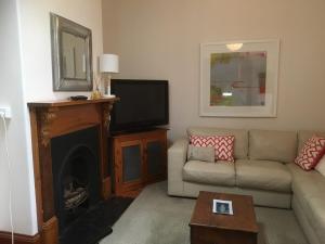 a living room with a couch and a television at Maylands Cottage in Evandale