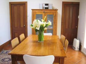 a wooden table with a vase of flowers on it at Maylands Cottage in Evandale