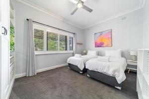 Un dormitorio blanco con dos camas y una ventana. en 5min to CBD and Sleeps 9 with Spa and EV charger, en Quarry Hill