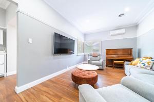 Una sala de estar con un sofá y un piano. en 5min to CBD and Sleeps 9 with Spa and EV charger, en Quarry Hill