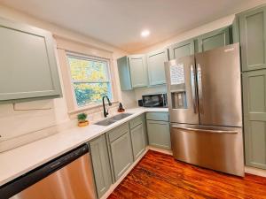 een keuken met groene kasten en een roestvrijstalen koelkast bij Cozy 3BR Cottage with Firepit Sleeps 10 Close to Lake Fun in Scottsboro