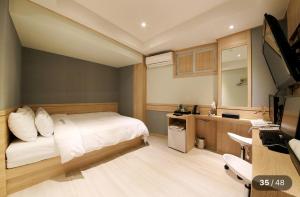 Un dormitorio con una cama, un escritorio y un televisor. en KANU hotel, en Seúl