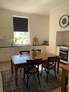 MintaroTickles Cottage in a beautiful Rural Setting的厨房配有桌椅和墙上的时钟