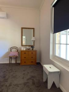 a room with a dresser and a mirror and a chair at Tickles Cottage in a beautiful Rural Setting in Mintaro +5 photos