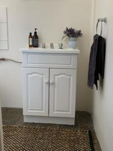 a bathroom with a white sink and a bathroom rug at Tickles Cottage in a beautiful Rural Setting in Mintaro