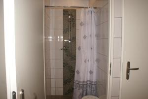 a shower with a white shower curtain in a bathroom at Hostel Kamienna Centrum in Katowice