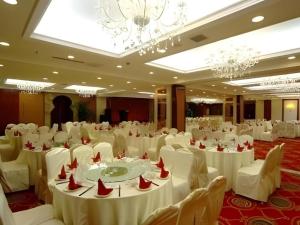 Changchun Global Hotel في تشانغتشون: قاعة حفلات بها طاولات وكراسي وثريات بيضاء