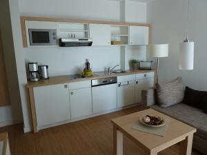 eine Küche mit weißen Schränken und einem Tisch im Wohnzimmer in der Unterkunft Hotel Goor und Apartmenthaus in Lauterbach