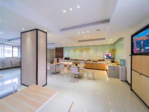 ein Restaurant mit Tischen und Stühlen und einer Küche in der Unterkunft City Comfort Inn Zhongshan Lihe Square Walmart Branch in Zhongshan