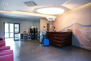 two people standing at a counter in an office at Hotel Sokołowska Airport Modlin in Nowy Dwór Mazowiecki