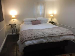 a bedroom with a bed with pillows on it at Peppertree Cottage in a beautiful Rural Setting in Mintaro