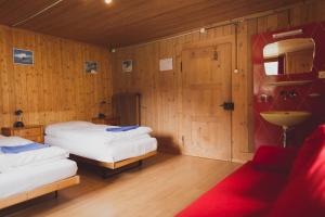 two beds in a room with wooden walls and wooden floors at The Lodge in Churwalden