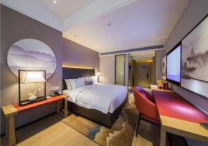 um quarto com uma cama, uma escrivaninha e uma TV em Echeng Hotel Changsha Evening News em Changsha