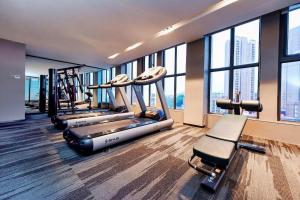 un gimnasio con filas de máquinas y ventanas en Echarm Hotel Anshun High-speed Railway Station Jichang Road, en Anshun
