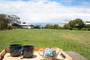 two mugs on a tray on a table with a field at Ocean Vista Escape Jan Juc in Bellbrae