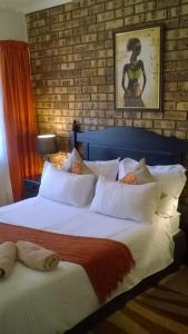 a bedroom with two beds and a brick wall at Flamboyant Apartments in St Lucia