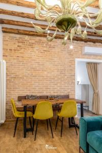 a dining room with a wooden table and yellow chairs at MISTRO House & Courtyard - by Sleep in MURANO in Murano