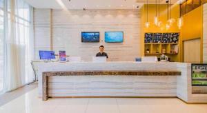 Um homem está atrás de um balcão num restaurante. em City Comfort Inn Changsha Railway Station Amiling Metro Station em Changsha