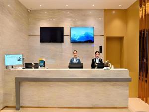 dwóch mężczyzn siedzących przy recepcji z laptopami w obiekcie City Comfort Inn Kunming High Speed Railway South Station Yongxin Harvard w mieście Kunming