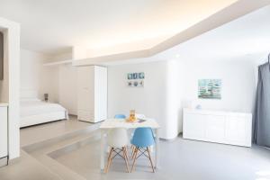 Habitación blanca con 2 sillas, mesa y cama en Marina Loft Sicily en Marina di Ragusa