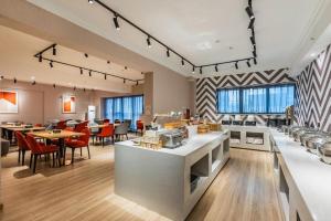 un ristorante con tavoli e sedie in una caffetteria di Borrman Hotel Ji'nan Aoti Center East Provincial Hospital a Jinan