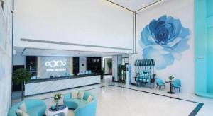 um grande saguão com uma flor azul na parede em Xana Hotelle Jinan Wuanfu Interchange Huafu International Square em Jinan