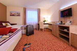 a hotel room with a bed and a desk at Mercure Hotel Hamburg am Volkspark in Hamburg