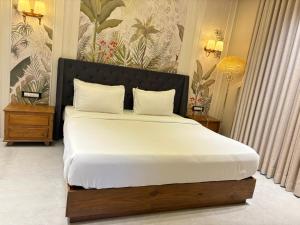 um quarto com uma cama grande com lençóis brancos em The Bhagwati Cottage & Villa em Ābu Road