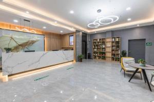 QiweiにあるGreenTree Inn Express Zhangjiagang Hexing Town Shazhou Professional Institue of Technologyの大きな大理石のカウンターとテーブルと椅子のあるロビー
