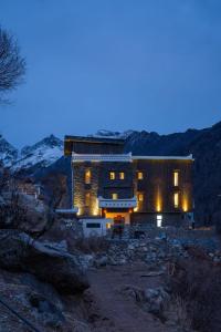 a house is lit up at night in the mountains at Siguniang Mountain Snow Inn in Mount Siguniang