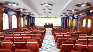a lecture hall with red chairs and a podium at TNV Casita Inn in Yercaud