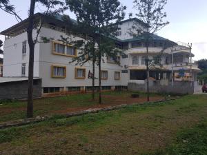 a large white building with trees in front of it at TNV Casita Inn in Yercaud