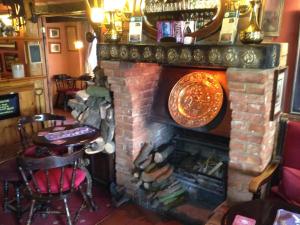 
a restaurant with a fire place in the middle of it at The Olde Windmill Inn in Great Cressingham
