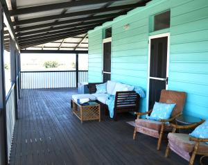 a porch of a blue house with chairs and a couch at Smithtown Champagne Bed and Bubbles in Smithtown