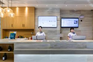 zwei Männer stehen mit ihren Laptops an einem Tresen in der Unterkunft City Comfort Inn Handan New Century Plaza in Sucao