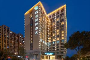 a tall building with a clock on top of it at City Comfort Inn Yancheng Xihuan Road Wanda Plaza in Yancheng