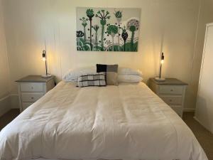 a bedroom with a large white bed with two lamps at The Vale Farmhouse Rural Setting in Farrell Flat