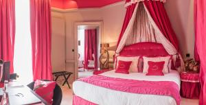 - une chambre avec un lit à baldaquin rose et des oreillers rouges dans l'établissement Le Stelsia Resort, à Saint-Sylvestre-sur-Lot