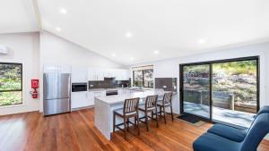 an open kitchen with white cabinets and a blue couch at 'Treetops On The Bay - Water Views' by HolidayCo in Hardys Bay
