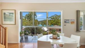 'Pretty Beach Bay Vista' by HolidayCo في Pretty Beach: غرفة طعام مع طاولة بيضاء ونافذة كبيرة +16 صورة
