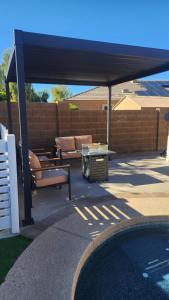 a patio with a blue canopy next to a pool at Private Mini Serene Oasis with Pool in Maricopa