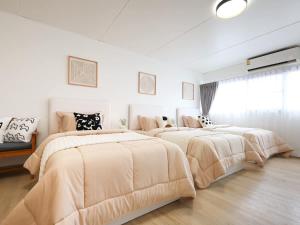 two beds in a bedroom with white walls and wood floors at 3 Beds,WiFi,Washing Machine,IMPACT Arena at T9 in Ban Bang Phang