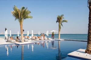 a swimming pool with palm trees and the ocean at Luxury Waters Edge Residence in Abu Dhabi