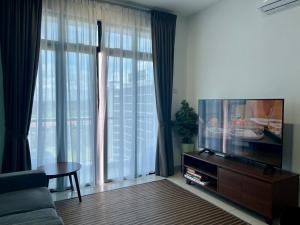 Bandar PenawarDesaru Central Apartment w Pool,CinemaScreen,Netflix & WiFi的配有平板电视和沙发的客厅