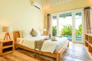 a bedroom with a bed and a large window at Villas Edenia - Luxe Villas with Private Pools in Gili Trawangan
