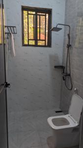 bagno bianco con servizi igienici e finestra di Dans place a Moshi