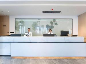 duas mulheres em pé em um escritório com seus laptops em GreenTree Inn Jinan West Station Exhibition Center em Jinan